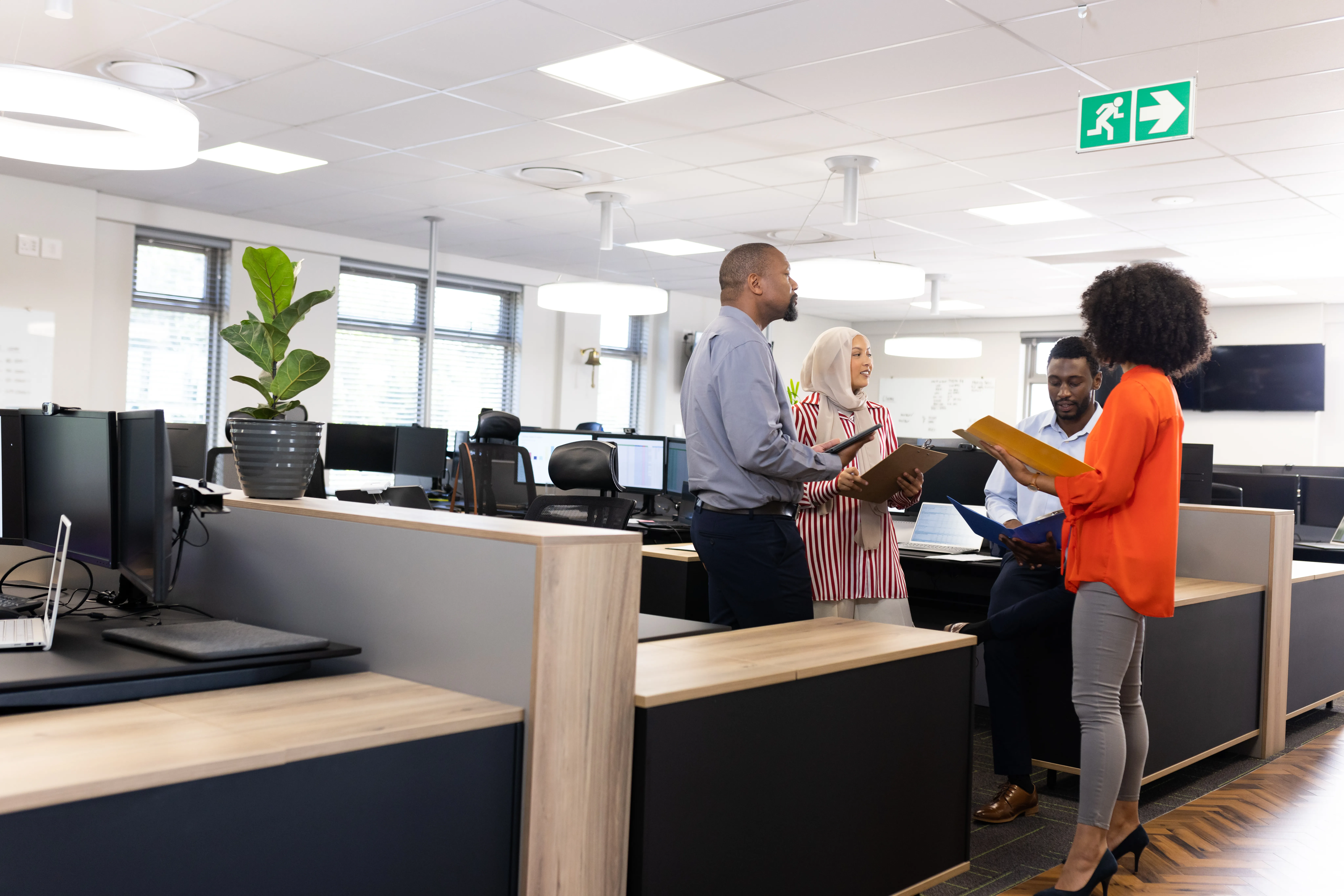Happy diverse female and male businesspeople talking and working in office